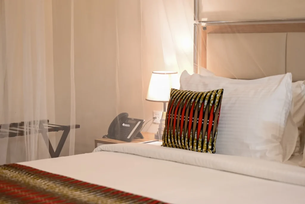 King bed with Rwandan-pattern cushion in the Junior Suite at The Hut Hotel, Kigali