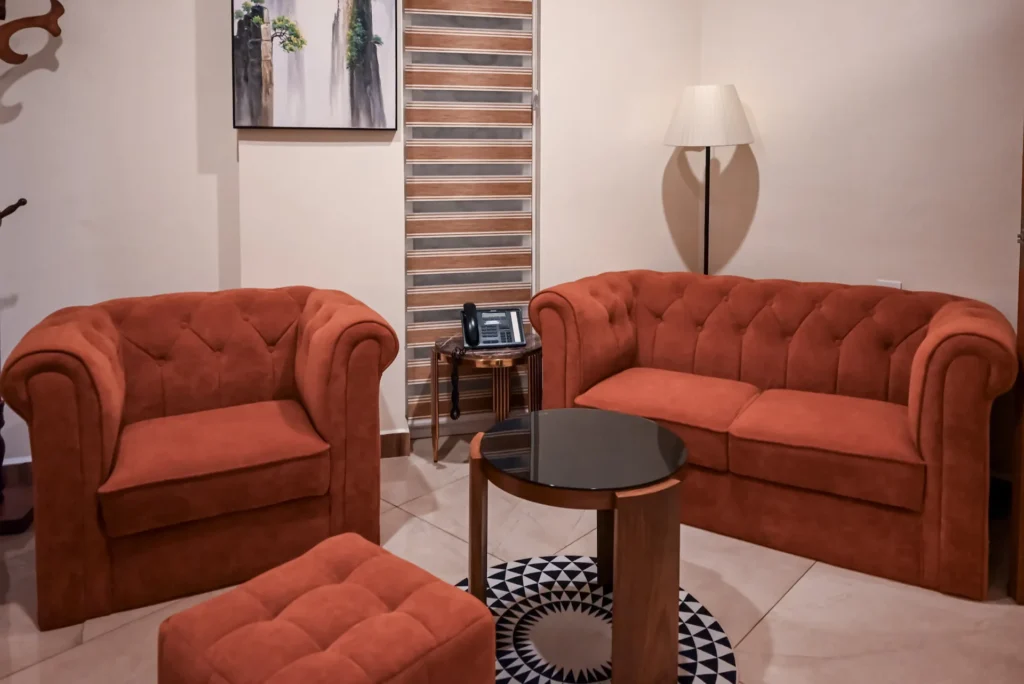 Junior Suite lounge with sofa, armchair and coffee table at The Hut Hotel, Kigali